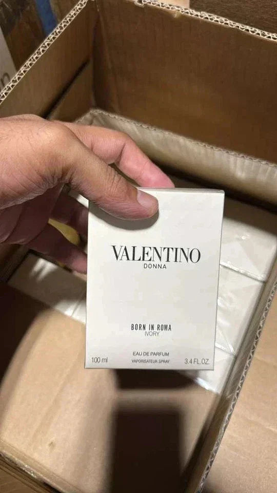 Valentino Donna perfume box held by a hand on a marble surface